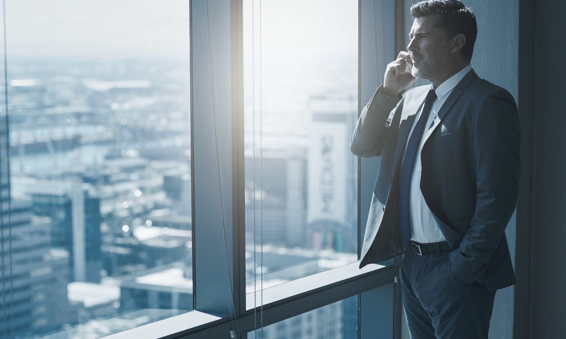 An executive standing at a high-rise window looking over the city, representing online reputation management for leaders